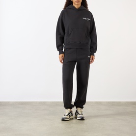 Model wearing Sporty and Rich Signature Logo Hoodie in Faded Black with matching joggers and chunky trainers.