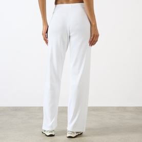Model wearing Sporty and Rich Signature Logo Ring Lounge Pants in white, elasticated waist, wide-leg fit, styled with white trainers.