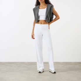 Model wearing Sporty and Rich Signature Logo Ring Lounge Pants in white with a grey vest and white crop top.