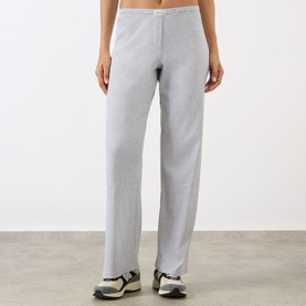 Model wearing Sporty and Rich Signature Logo Rib Sweatpants in grey, straight leg with elasticated waist, styled with grey trainers.