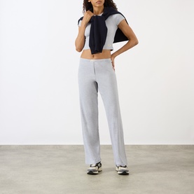 Model wearing Sporty and Rich Signature Logo Rib Sweatpants in grey, ribbed straight leg with elasticated waist, styled with navy crop top and
