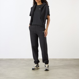 Model wearing Sporty and Rich Signature NY Logo T-Shirt in Faded Black, styled with matching joggers and trainers.