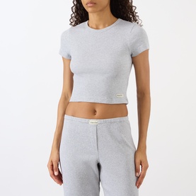 Model wearing Sporty and Rich Signature Logo Rib Baby T-Shirt in Heather Grey, cropped ribbed tee with round neck, styled with matching grey joggers