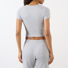 Model wearing Sporty and Rich Signature Logo Rib Baby T-Shirt in Heather Grey, back view, with matching grey sweatpants.