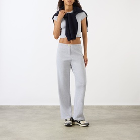 Model wearing Sporty and Rich Signature Logo Rib Baby T-Shirt in Heather Grey, styled with wide-leg grey trousers and navy tied top layer.