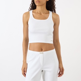 Model wearing Sporty and Rich Signature Logo Tank Top in white, cropped ribbed style with square neck, paired with white trousers