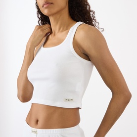 Model wearing Sporty and Rich Signature Logo Tank Top in white, cropped fit with round neck, sleeveless, small logo patch detail, styled with white