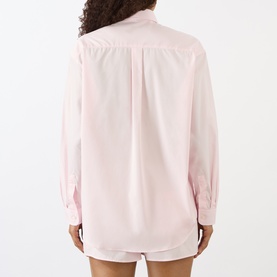 Model wearing Sporty and Rich Signature Logo Shirt in Clear Pink, rear view showing curved hemline, relaxed cotton fit and button fastenings.