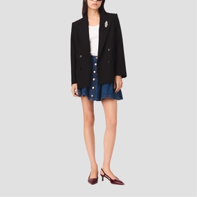 Model wearing Maje black double-breasted blazer and denim mini skirt, styled with a white top and red slingback heels.