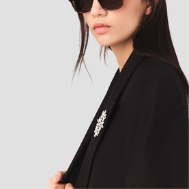 Model wearing Maje black blazer with crystal brooch detail, styled with brown cat-eye sunglasses