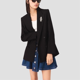 Model wearing Maje red women's blazer with crystal brooch detail, styled with white top and denim mini skirt