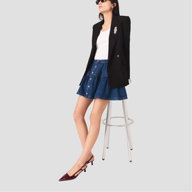 Model wearing Maje Womens French Dress in blue denim mini skirt style, styled with black blazer, white top and red slingback heels