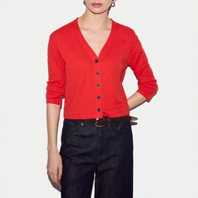 Model wearing Jigsaw red V-neck button-front cardigan with three-quarter sleeves, styled with dark navy wide-leg trousers and brown belt.