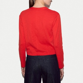Model wearing Jigsaw red fine knit jumper, back view, styled with dark navy wide-leg trousers.