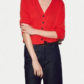 Model wearing Jigsaw red V-neck cardigan with black buttons, styled with dark navy wide-leg jeans and a brown belt.