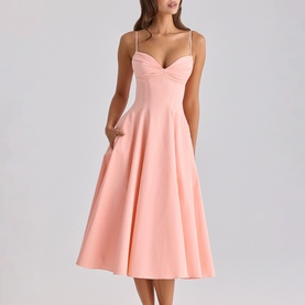 Model wearing House of CB peach midi dress with sweetheart neckline, thin straps, and full A-line skirt with side pockets