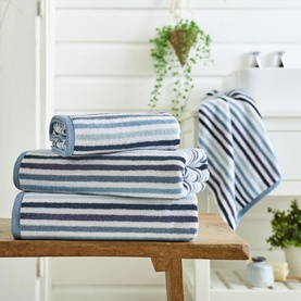 Deyongs Linear Stripe Towel Blue, stacked set in blue and white stripes, displayed on wooden bench in bright bathroom setting