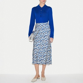 Model wearing Jigsaw blue long-sleeve polo dress with white and blue leopard-print midi skirt section and grey flat mules.