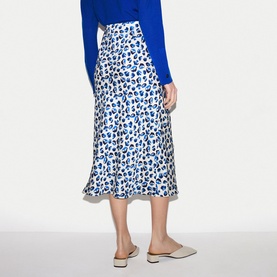 Model wearing Jigsaw blue leopard-print midi skirt, styled with a cobalt blue top and white mule heels, rear view.