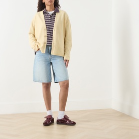 Model wearing Guest In Residence butter cashmere knit jacket, styled with striped polo, light-wash denim shorts and burgundy loafers