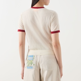 Model wearing Guest In Residence Airy Ringer T-Shirt in cream cashmere with burgundy contrast trims, back view, styled with linen trousers.