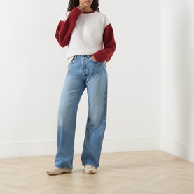Model wearing Guest In Residence cashmere T-shirt in multi colourblock cream and red, styled with light blue wide-leg jeans and beige loafers
