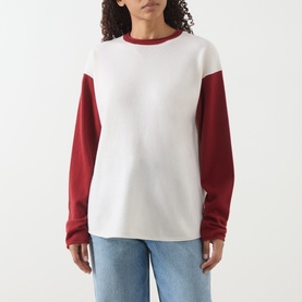 Model wearing Guest In Residence cashmere T-shirt in white and red colourblock with long sleeves, styled with light blue jeans