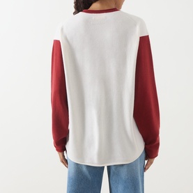 Model wearing Guest In Residence cashmere T-shirt in white and red colourblock, long sleeves, shown from behind, styled with blue jeans