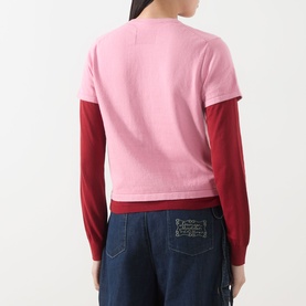 Model wearing Guest In Residence Double Layer Top in pink, two-tone with red layered sleeves, logo detail at back, styled with blue denim jeans.