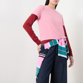 Model wearing Guest In Residence Double Layer Top in pink with burgundy two-tone sleeves, styled with navy wide-leg trousers and a striped shirt tied