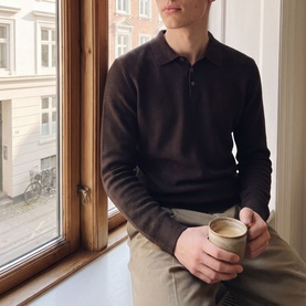 Model wearing Jack & Jones Riley Knitted Polo Shirt in Ganache, long-sleeve cotton knit with polo collar, styled with beige trousers
