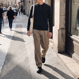 Model wearing Jack & Jones Riley Logo Knitted Polo Shirt in Scarab, styled with taupe trousers and black shoes, walking on a city street.