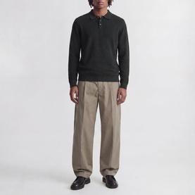 Model wearing Jack & Jones Riley Logo Knitted Polo Shirt in Scarab, long-sleeved with quarter-button collar, styled with taupe wide-leg trousers.