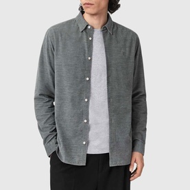 Model wearing All Saints light grey long sleeve button-up shirt, styled with grey T-shirt and black trousers.