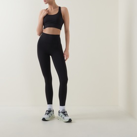 Model wearing Lululemon Energy Longline Sports Bra in black, styled with matching black leggings and white trainers.