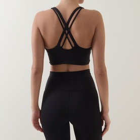 Model wearing Lululemon Energy Longline Sports Bra in black, showing cross-back strap detail, styled with matching black leggings.