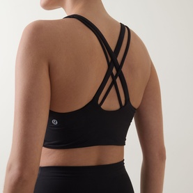 Model wearing Lululemon Energy Longline Sports Bra in black, shown from behind with cross-strap back detail, paired with black leggings.
