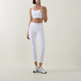 Model wearing Lululemon Energy Longline Bra in white, styled with matching white high-waist cropped leggings and silver trainers.