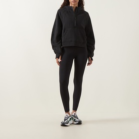 Model wearing Lululemon black leggings, styled with a black half-zip hoodie and multicoloured chunky trainers.