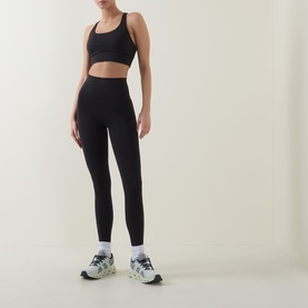 Model wearing Lululemon Wunder Train No Line High-Rise Tight 25" in black, styled with a black sports bra and white trainers.