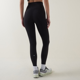 Model wearing Lululemon Wunder Train No Line High-Rise Tight 25" in black, shown from behind, styled with white trainers.