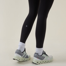 Model wearing Lululemon Wunder Train No Line High-Rise Tight 25" in black, styled with white ankle socks and grey trainers