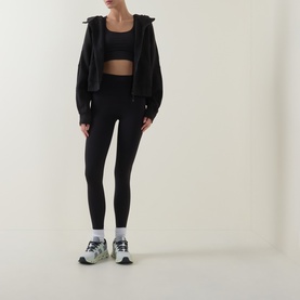 Model wearing Lululemon Wunder Train No Line High-Rise Tight 25" in black, styled with matching black sports bra, zip hoodie and white trainers.