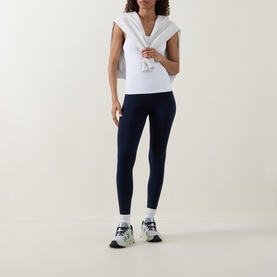 Model wearing Lululemon True Navy leggings with white sleeveless top, white hoodie tied at shoulders, white socks and chunky trainers.