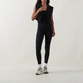 Model wearing Lululemon black leggings, styled with a black vest top and white socks with grey chunky trainers