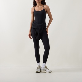 Model wearing Lululemon black cami top with black leggings and a jacket tied at the waist, styled with white socks and beige trainers.