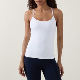 Model wearing Lululemon white strappy cami top with scoop neck and cross-back straps, styled with navy leggings.