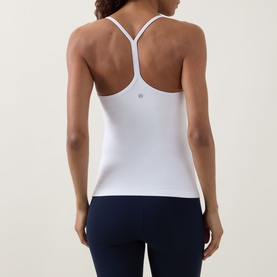 Model wearing Lululemon white racerback vest top, rear view, styled with navy leggings.