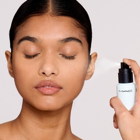 Model with MAC Setting Spray held near face, white pump bottle with black cap, eyes closed, misted complexion