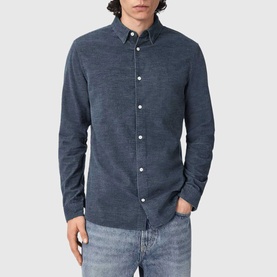 Model wearing All Saints moonstone blue long sleeve button-down shirt, styled with light wash jeans.